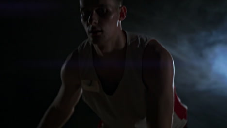 Skill-dribbling-basketball-player-in-the-dark-on-the-basketball-court-with-backlit-back-in-the-smoke.-Slow-motion-streetball
